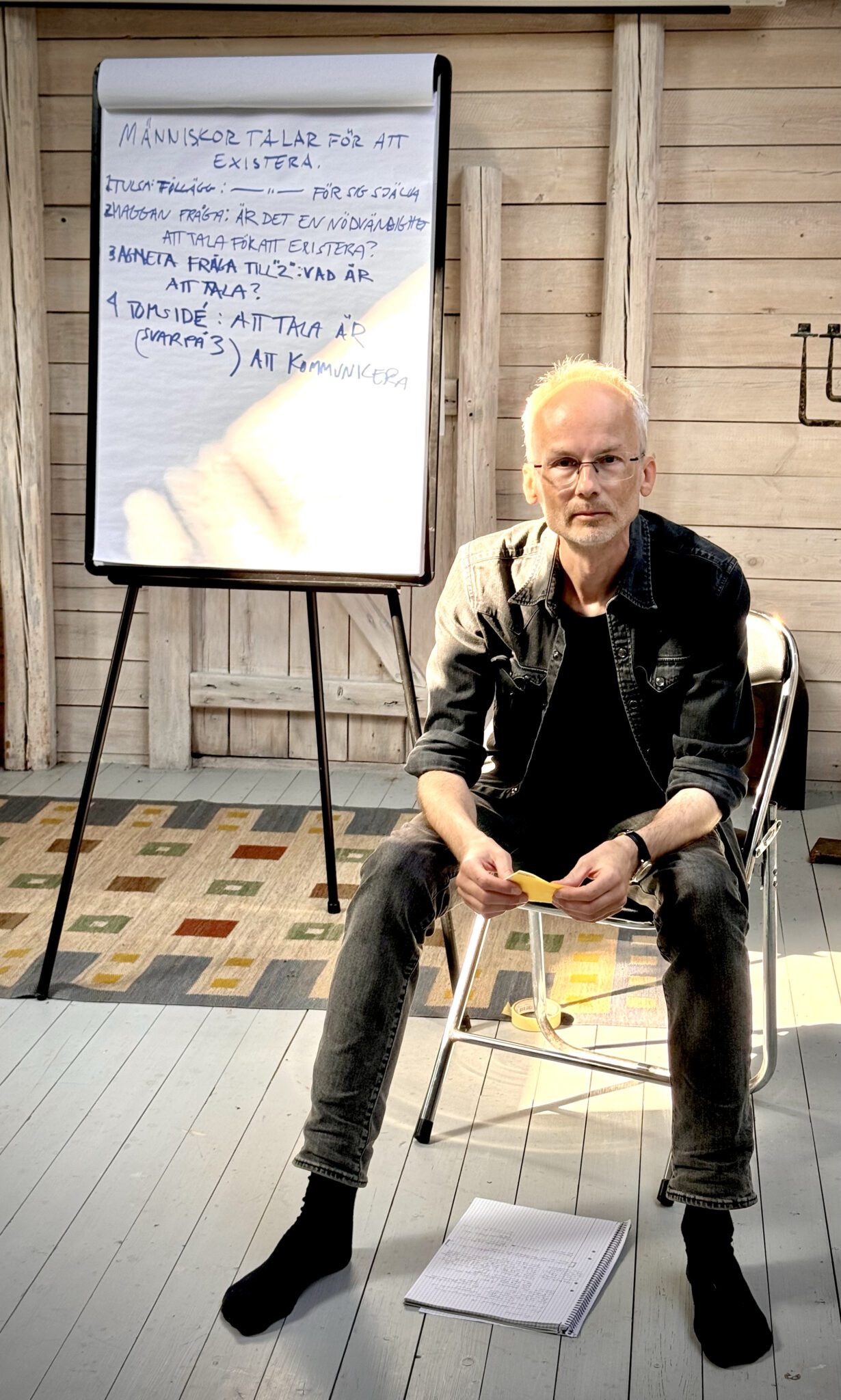 Filosofiske praktikern Mathias Tistelgren håller i en workshop om sokratisk dialog. Han sitter på en stol med ett blädderblock bakom sig.